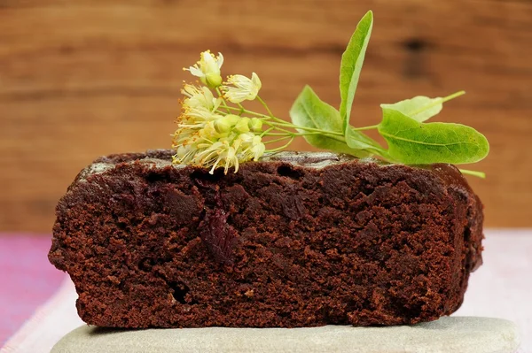 Темный Шоколадный торт с цветами липы на деревянных фоне — стоковое фото