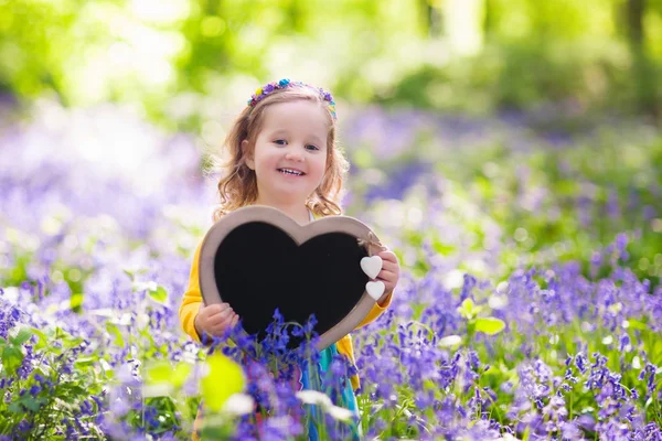 Little girl with blank board in flower field Стоковое Фото