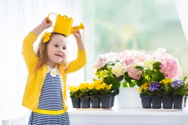 Little girl watering blooming flowers at home Лицензионные Стоковые Фото