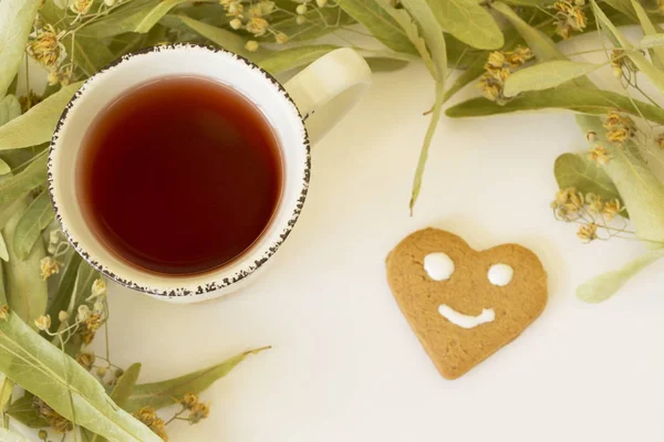 Рама сухой липа Цветет с чашкой чая и печенья улыбка лица на белом фоне. Вид сверху — стоковое фото