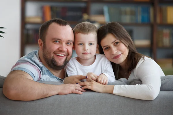 Картина улыбаясь семьи с сыном, сидя на серый диван — стоковое фото